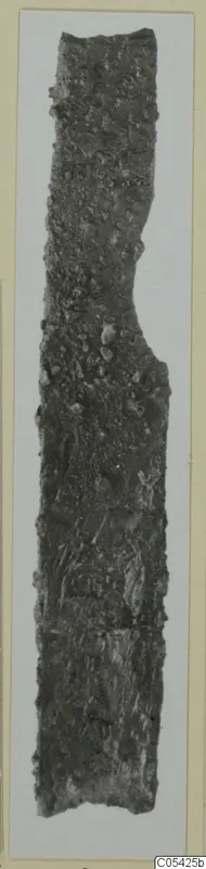 Corroded iron knife, long and narrow, with an encrusted, pitted surface