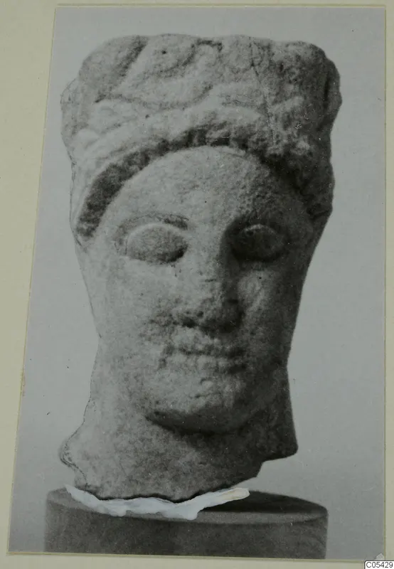Limestone head from Mersinaki with wavy hair or headdress and large almond-shaped eyes, shown on a cylindrical base