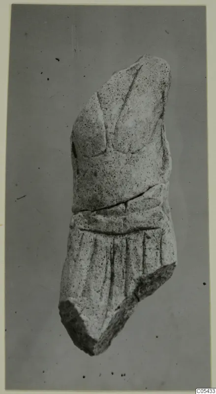 Limestone sculpture fragment, a broken torso-like piece with carved folds of drapery on the lower part