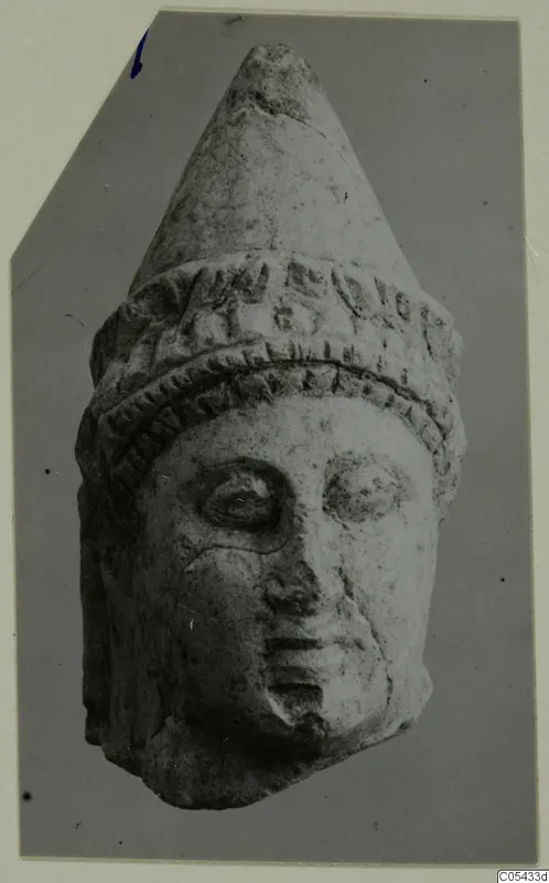 Limestone head with a tall conical headdress and a band of relief decoration, from Mersinaki