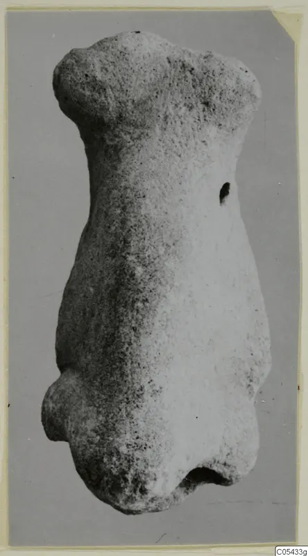 Limestone figurine: a headless, armless torso of pale stone, photographed against a grey background.