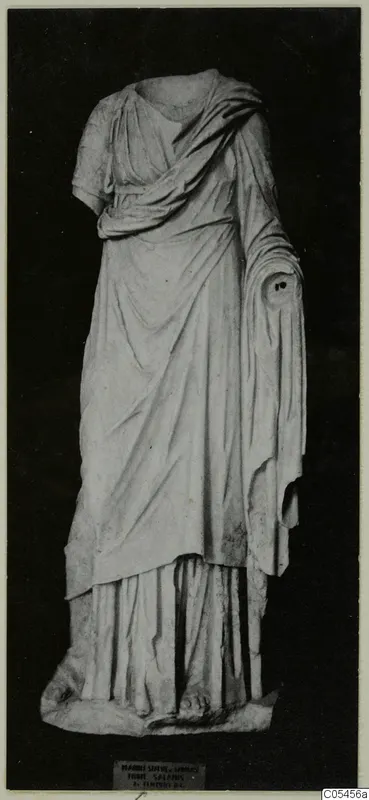 Headless draped marble statue of a standing figure, photographed against a dark background