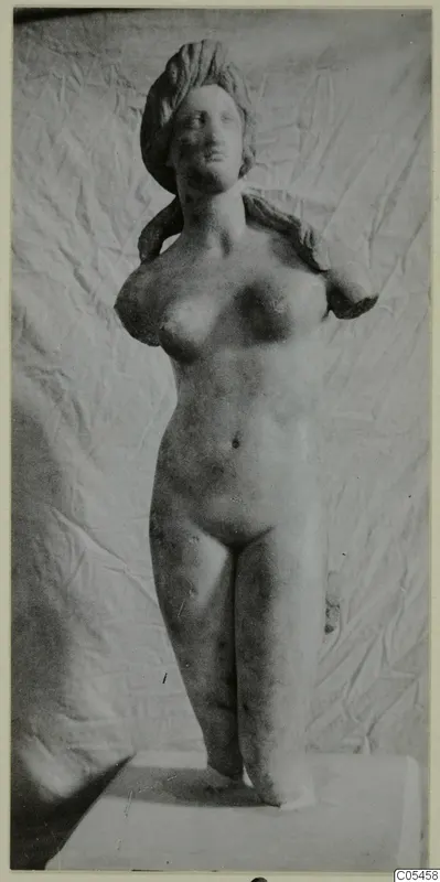 Marble statue of a standing nude female figure with the arms missing, set on a plinth.
