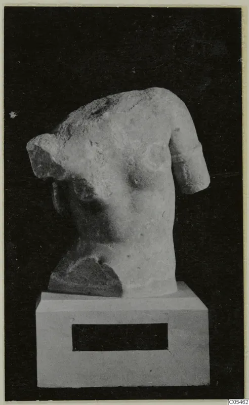Marble sculpture of a human torso with the head and arms broken, on a white plinth against a black background.