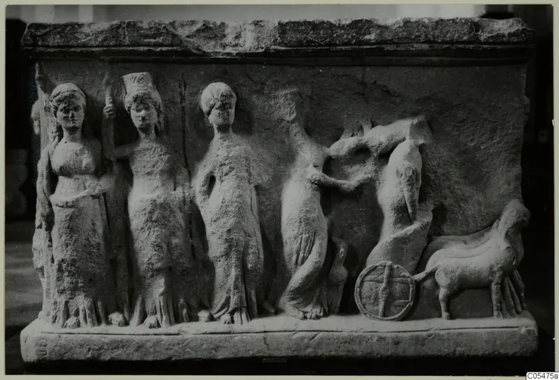 Carved stone relief block with standing draped female figures, a horse and a chariot wheel