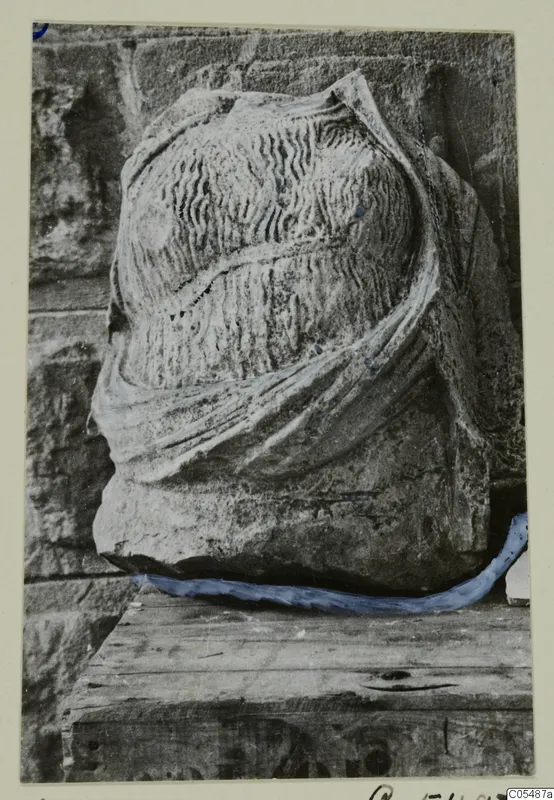 Carved stone fragment from Arsos, with wavy incised lines and a raised band of drapery across it