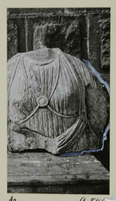 Headless stone statue fragment from Arsos, a torso with pleated drapery and a round disc at the chest