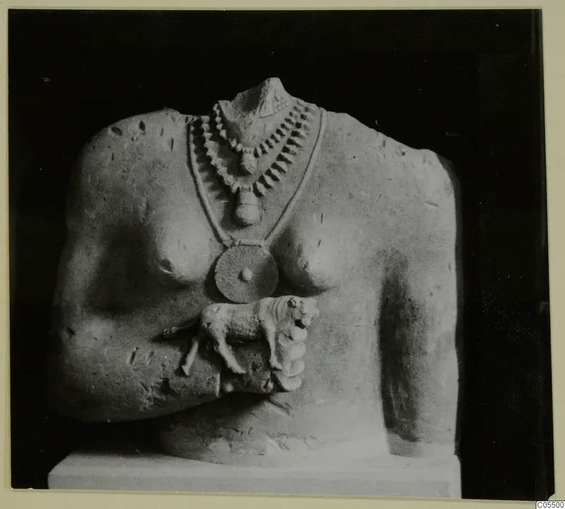 Headless limestone sculpture of a torso with a layered necklace and a small animal figure at the chest.