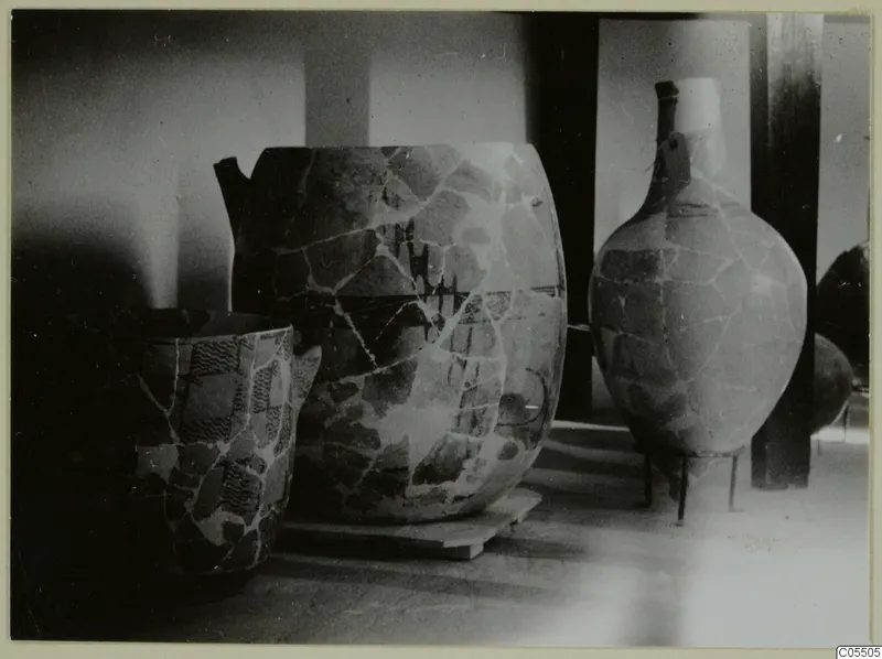 Stone Age pottery: three large mended vessels on wooden stands and plinths in a display room