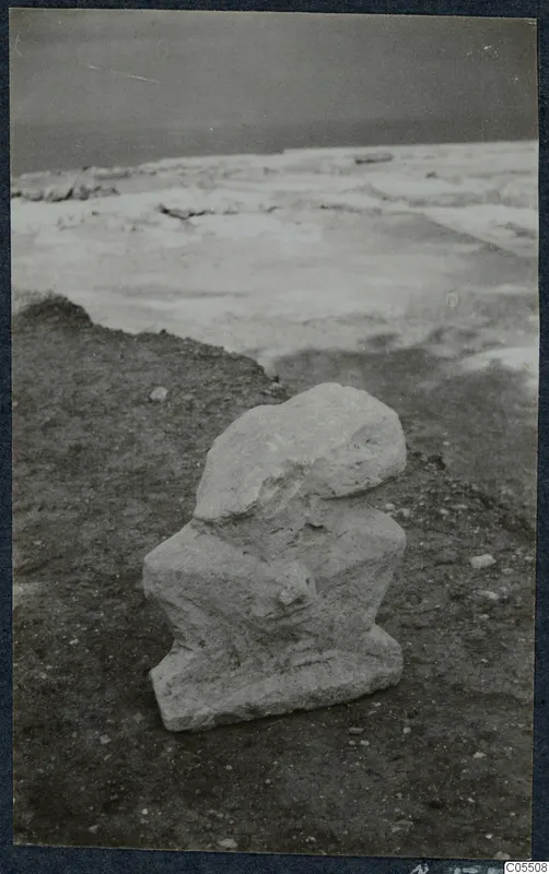 Weathered pale stone fragment lying in situ on dirt ground at Vouni Palace