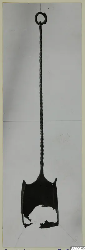 Bronze shovel with a ring at the top, a long twisted shaft and a scoop-shaped blade with a broken section.
