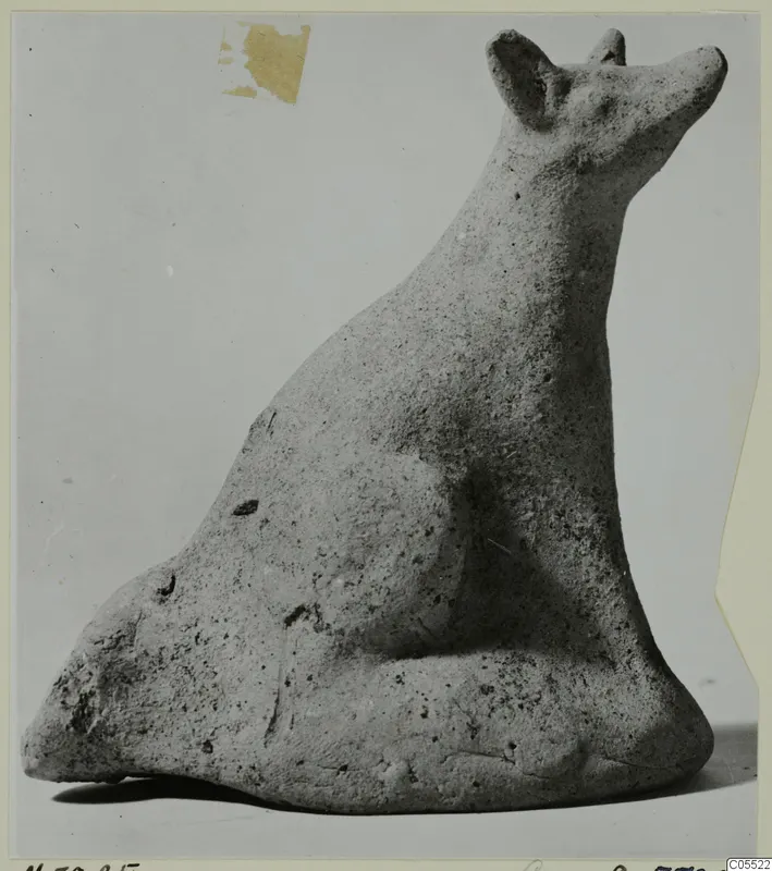 Terracotta figurine of a seated animal with upright pointed ears and a raised snout