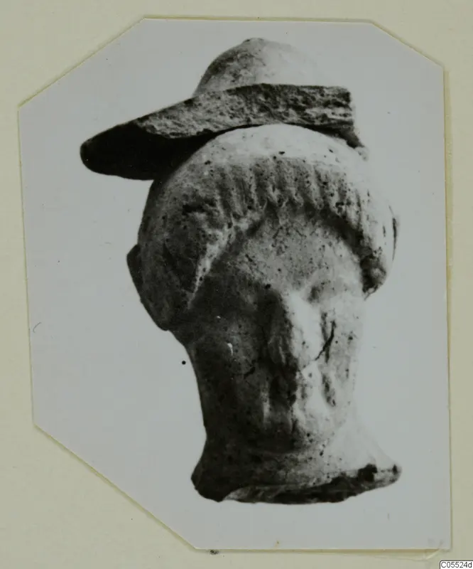 Small head with a wide flat projecting element and wavy hair bands, from Mersinaki