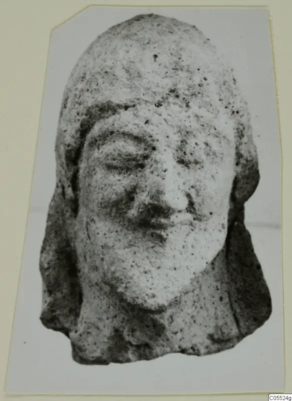 Terracotta head of a figure from Mersinaki, shown frontally with downcast eyes and hair falling to the shoulders