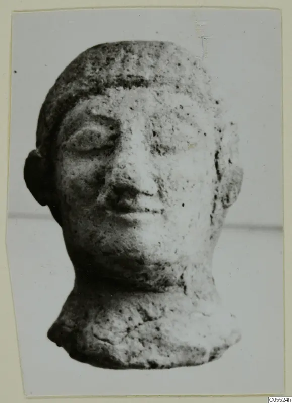 Small terracotta head of a figure from Mersinaki, shown face forward against a plain background