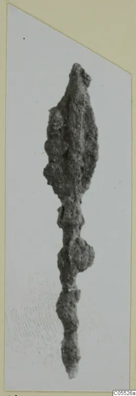 Corroded iron arrowhead from Marion, with a long tang, shown on a mounted photograph.