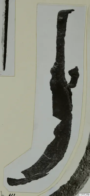 Corroded metal object with a curved lower end and a small bent projection, shown on a mounted card, from Marion