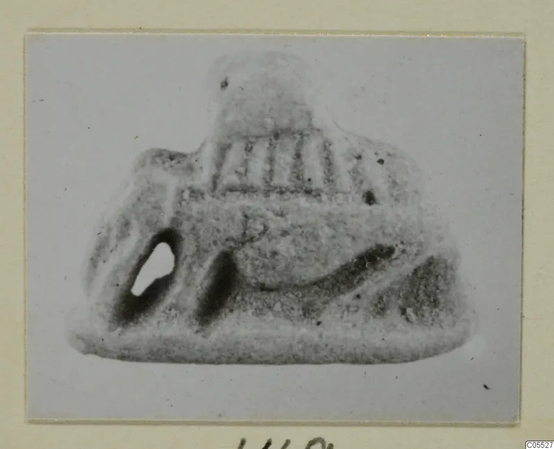 Small grey object from Amathus with a pierced hole and vertical ridges, shown on a card mount