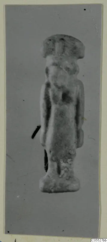 Small standing figure of Sekhmet, seen frontally against a grey background on a mounted print