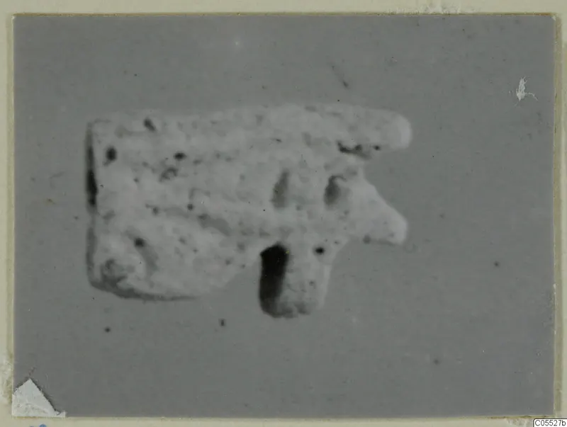 Small pale object on a grey backdrop, from Amathus tombs 1–9 finds, with a rounded projection and a dark hole below