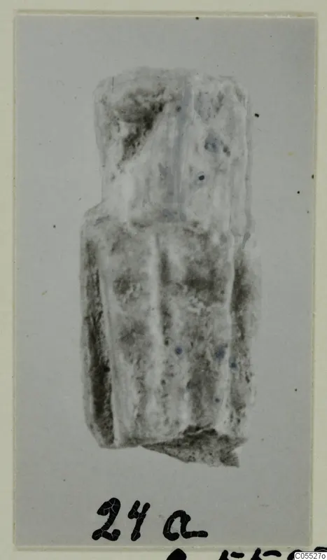 Fragmentary sculpture, possibly a figure, pale and rough-surfaced, shown on a grey card mount