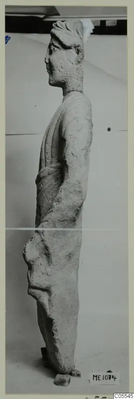 Side view of a standing limestone statue of a figure from Mersinaki