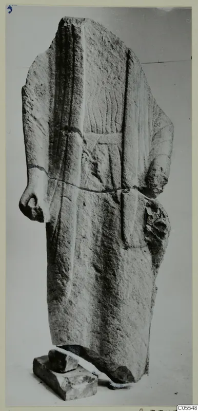 Limestone statue fragment from Mersinaki: a standing figure with head and forearms broken off, in a long garment with vertical folds.