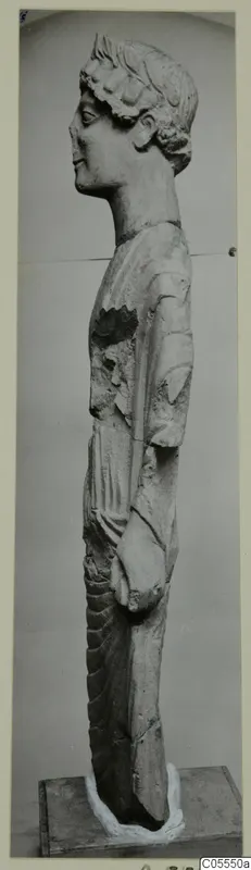 Standing limestone statue from Mersinaki, seen in side profile, with a damaged upper torso.
