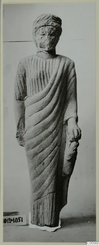 Limestone statue of a standing draped figure from Mersinaki, face worn and features indistinct.