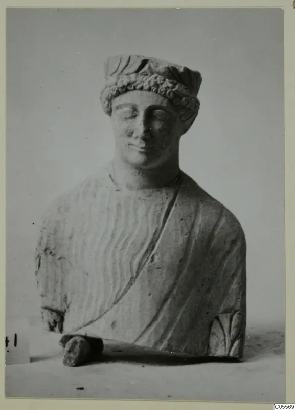 Limestone bust from Mersinaki with closed eyes, a curled headband and a draped garment