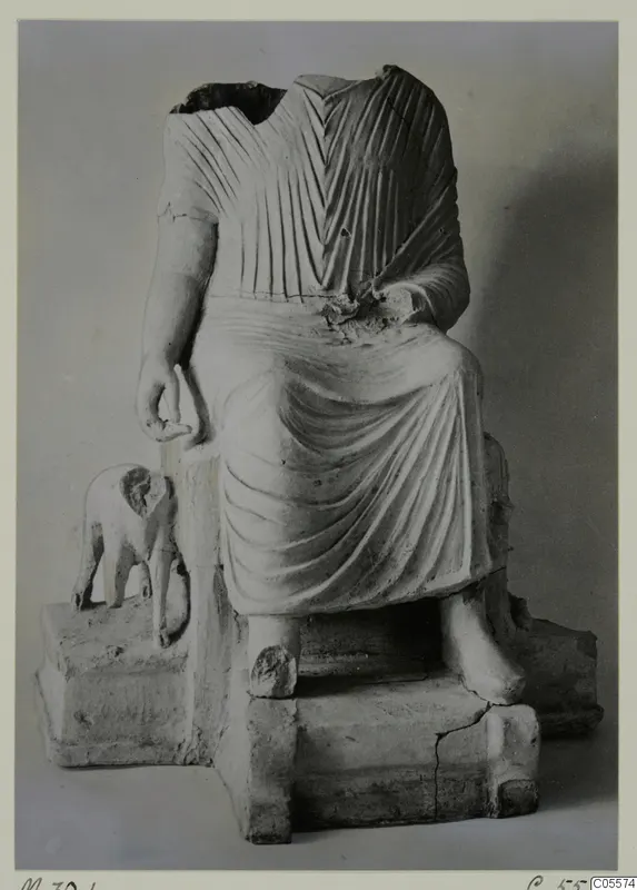 Terracotta statuette of a seated, headless draped figure with a small animal figure on its base.