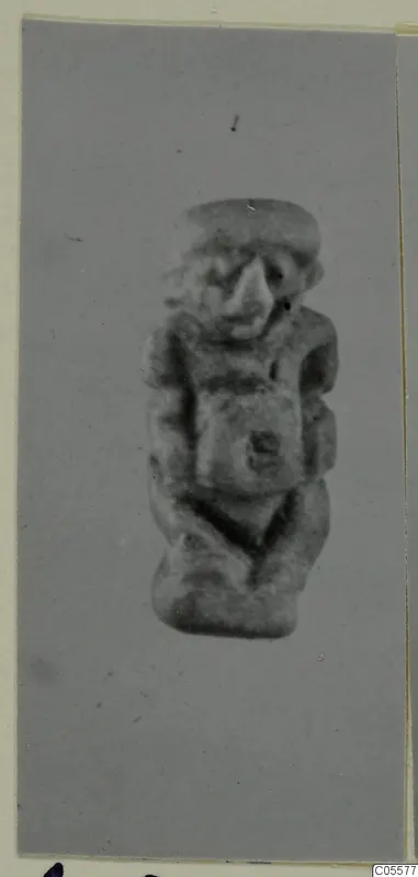 Small figurine of a squat figure with a large nose and a flat cap, arms folded across the chest.