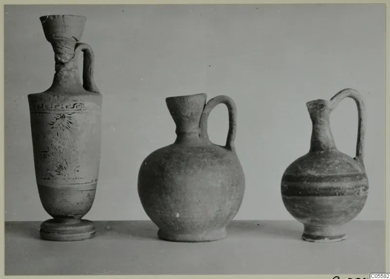 Three pottery vessels standing in a row on a plain surface, from Marion.