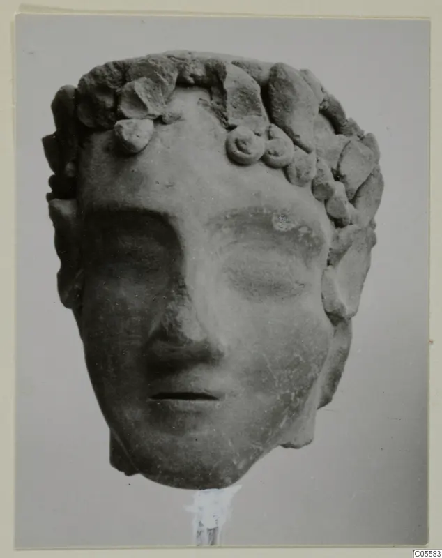 Head of a figure with a leafy wreath, from Mersinaki, photographed frontally.
