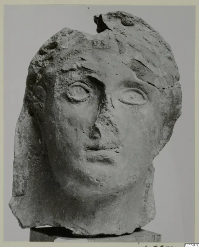 Carved head from Mersinaki, front view on a block, with the top and back of the head broken away.