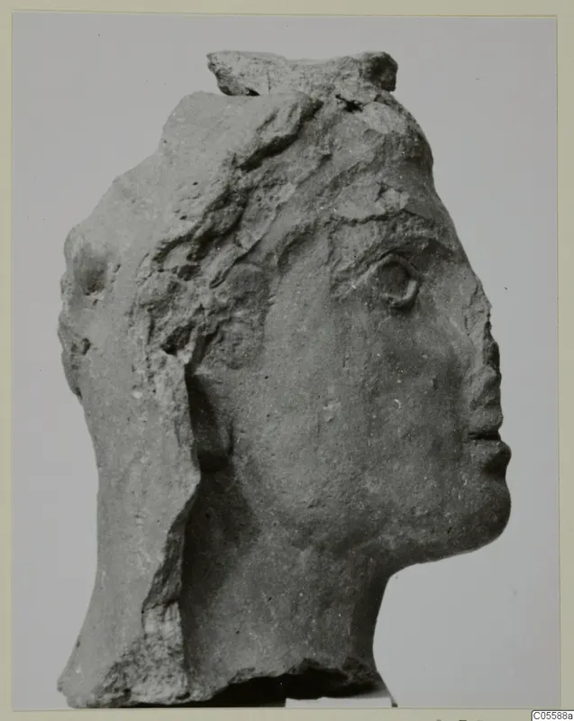 Carved stone head from Mersinaki, shown in profile facing right, broken at the top and back.