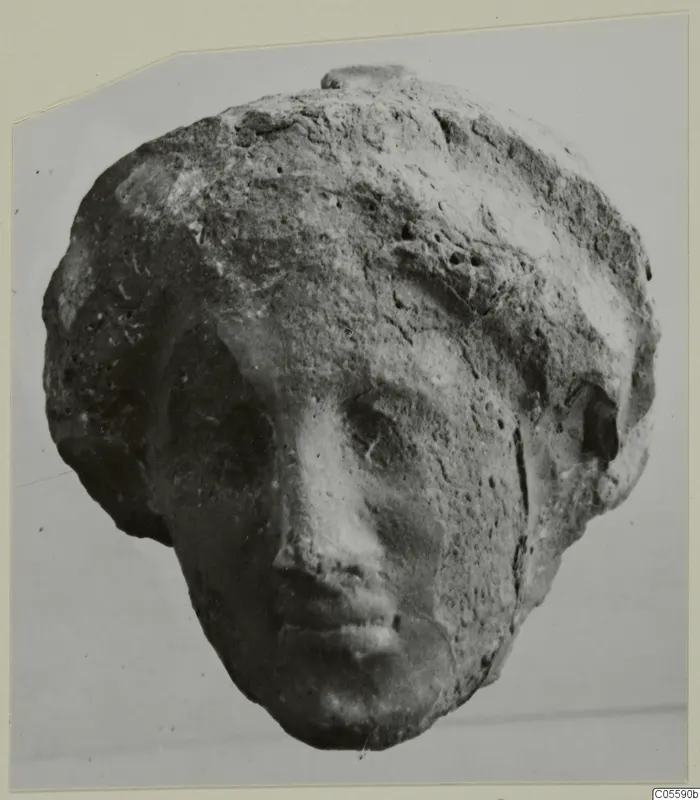 Head of a small figure in terracotta or limestone, with a worn face and pitted surface, from Mersinaki