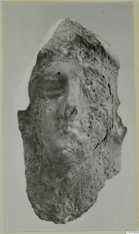 Terracotta head fragment from Mersinaki, showing a worn face with an eye, nose and mouth in low relief