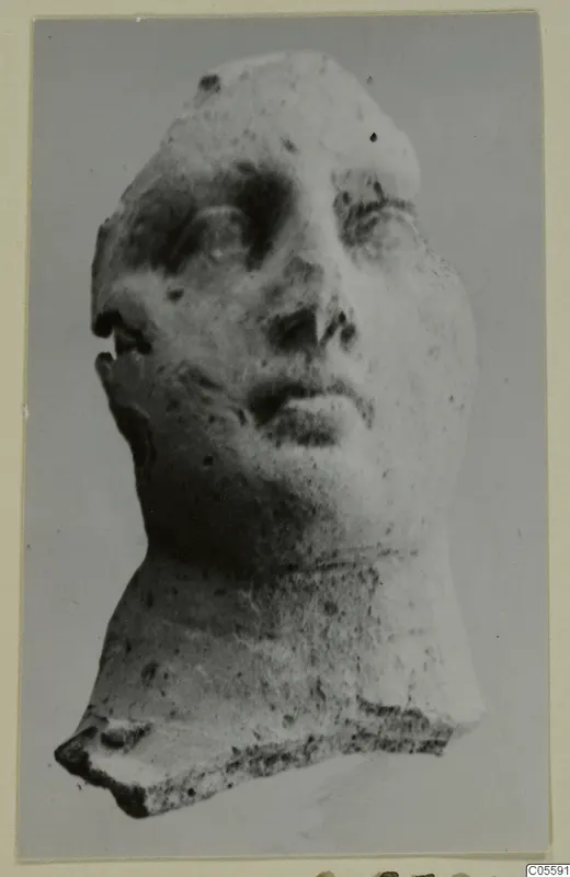 Head fragment from Mersinaki with face and neck, photographed against a plain grey background