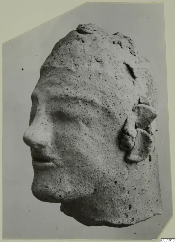 Terracotta head from Mersinaki, shown in three-quarter view facing left, with a rough, pitted surface and ear ornaments.