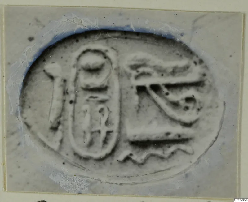 Scarab seal with an oval frame and incised signs, including an eye-like motif, shown in close-up.