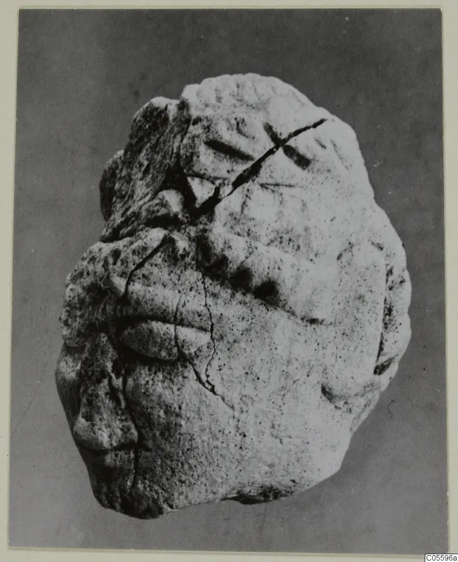 Limestone sculpture fragment from Mersinaki, with carved relief forms and a diagonal crack across the surface.