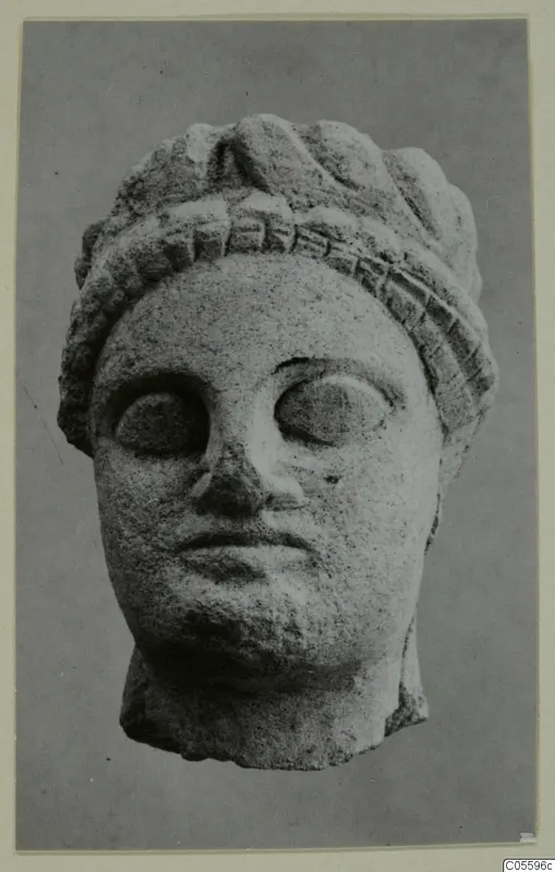 Limestone head from Mersinaki, photographed face-on against a plain grey background