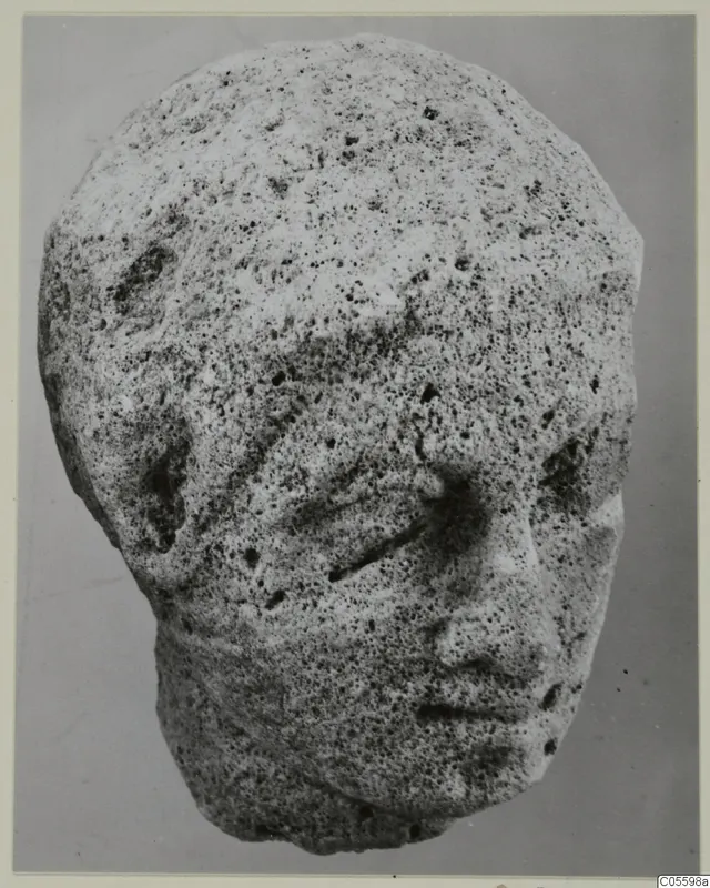 Limestone sculpture head from Mersinaki, face partly worn, photographed against a plain grey background