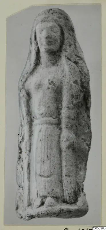 Standing figure with long hair and a belted garment, a small terracotta figurine photographed on a card mount