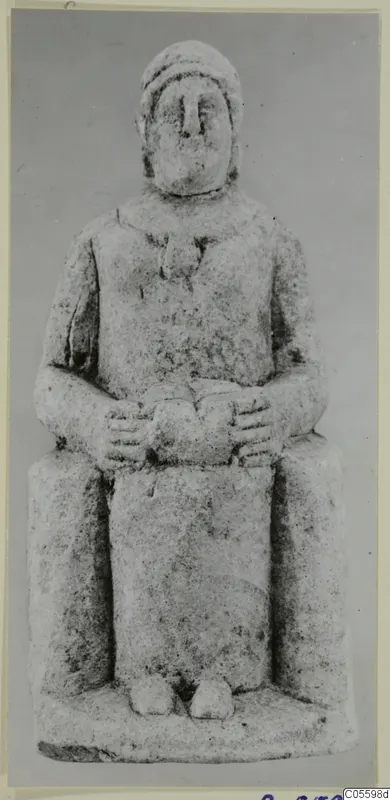 Seated limestone figure with hands clasped in its lap and a close-fitting head covering