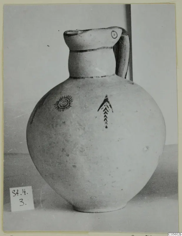 Pottery White Painted IV jug with a spiral motif and a chevron motif in dark paint on its round body