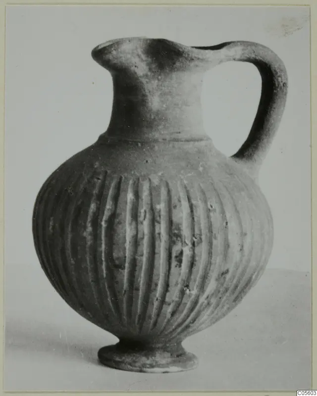 Jug with a trefoil mouth, one handle and vertical fluting on the body, standing on a small foot.