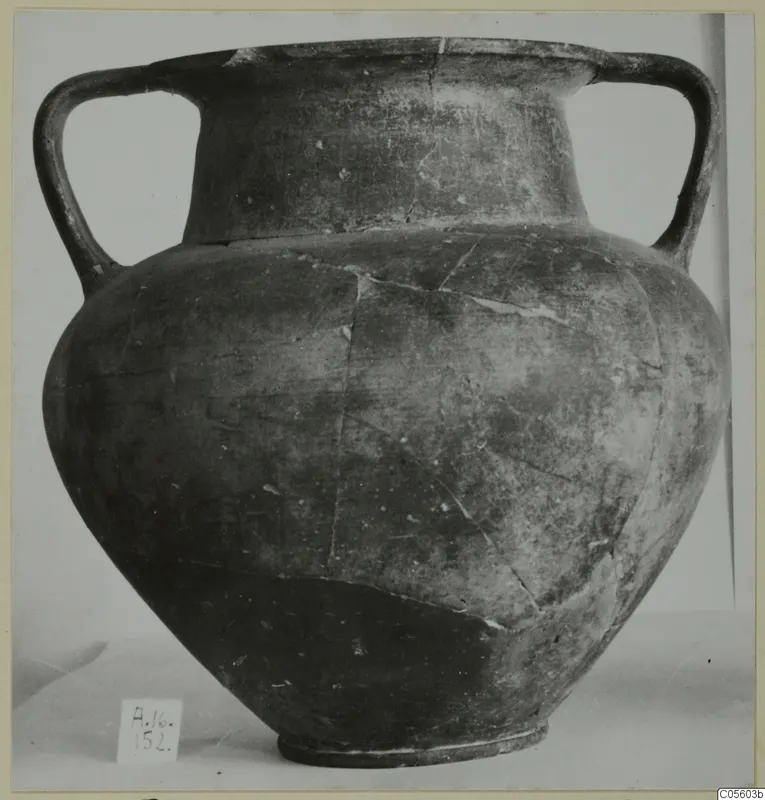 Two-handled pottery jar with a dark, worn surface, photographed on a plain background