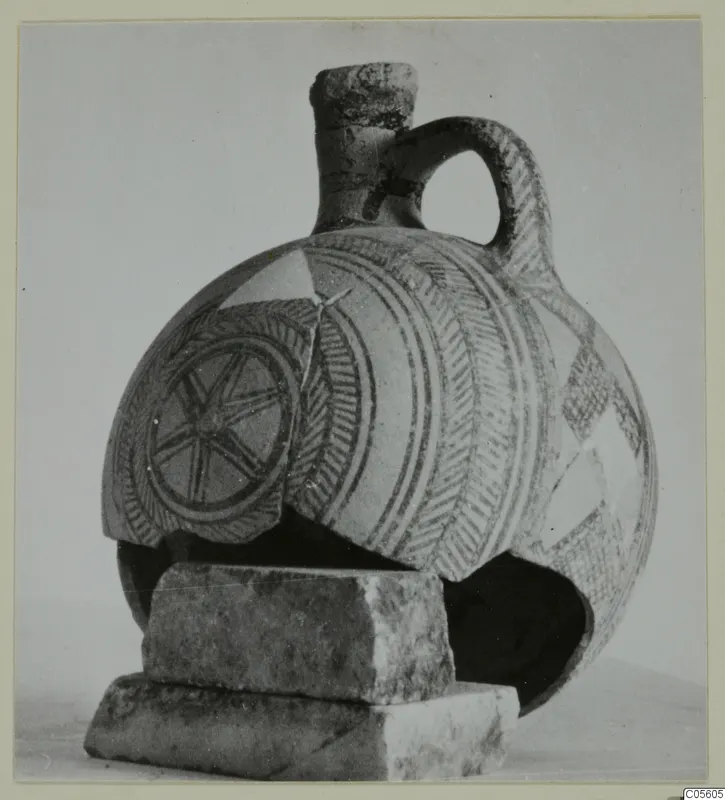 White Painted I jug with a loop handle and painted bands, shown on a stack of stone blocks